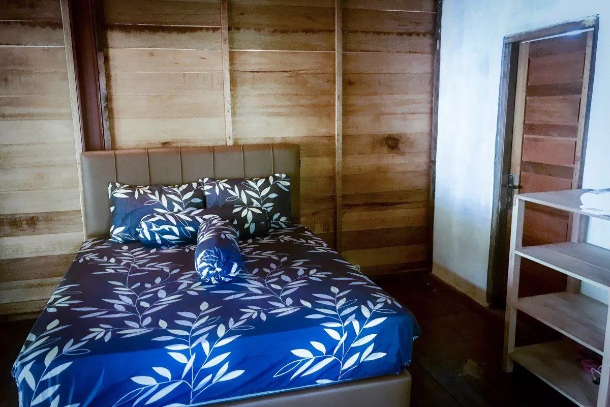 The queen-size bed in the Classic Bungalow, against the timber plank wall.