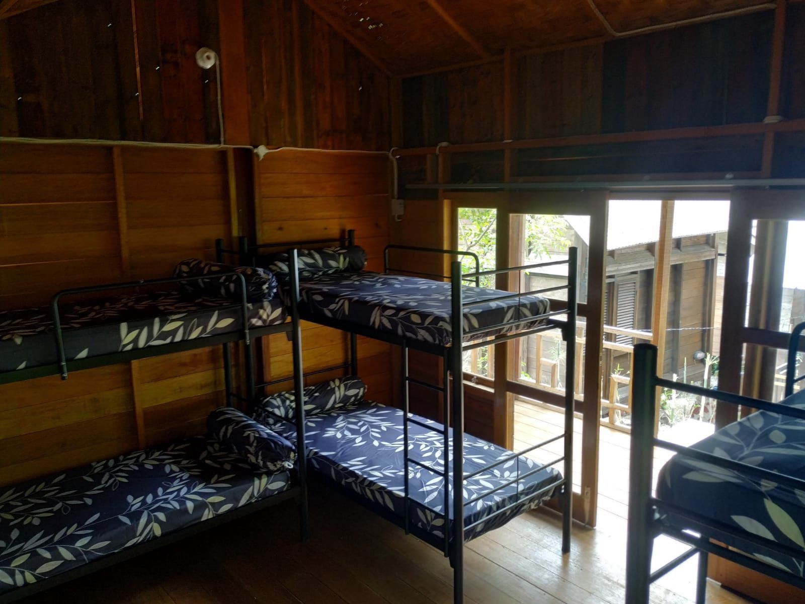 Metal bunk beds in the dormitory, with the doors open onto the terrace.