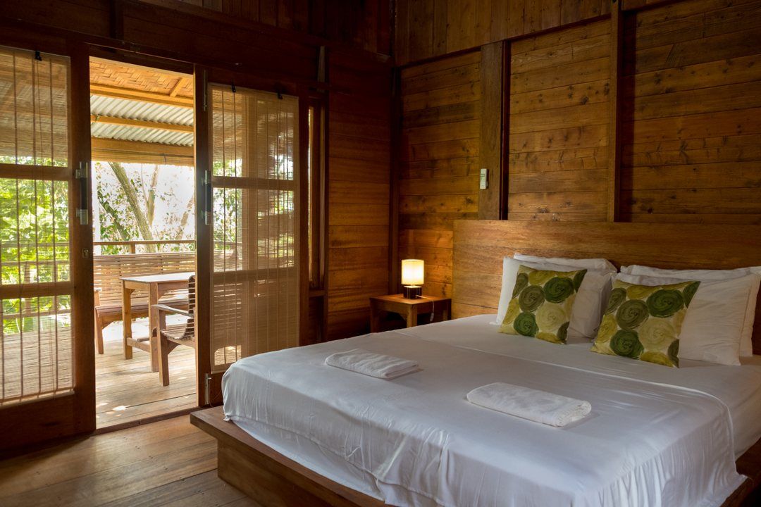The king-size bed in the Fancy Bungalow, with the doors open onto the balcony and the garden beyond.