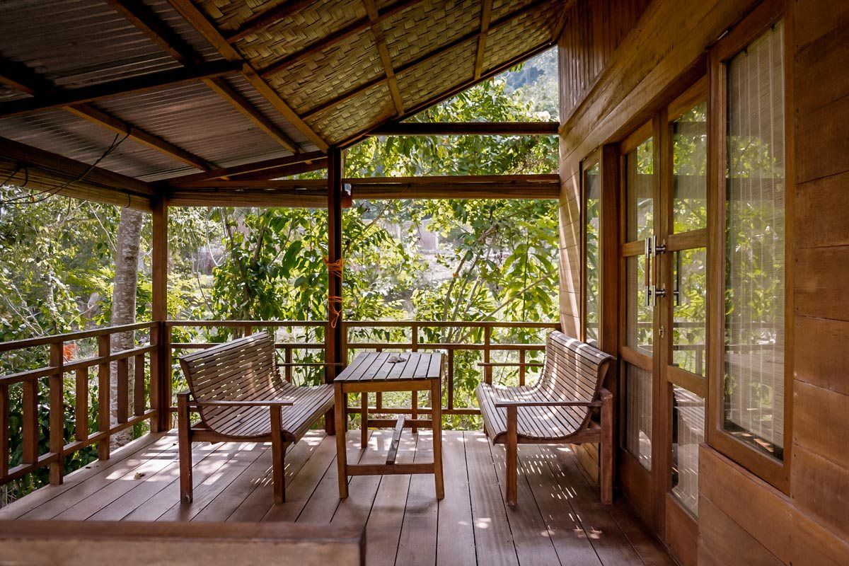 The big balcony of the Fancy Bungalow, with two wooden benches facing the garden.